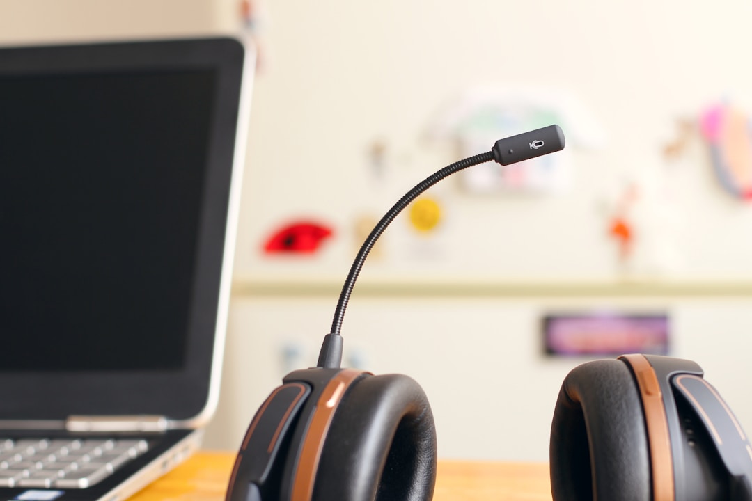 A laptop that has been positioned next to a headset that has a mic attached to it that's stationed within a contact center.